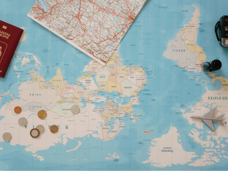 Carte du monde avec passeport, pièces de monnaie et avion miniature
